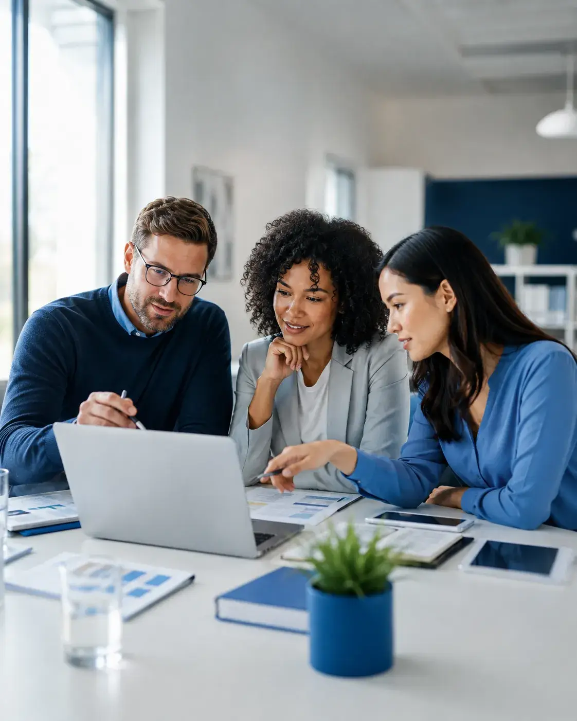Drie professionals bespreken samen informatie en inhoudelijke samenwerking rond een laptop in een moderne werkomgeving